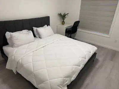 a white bed with a black headboard in a bedroom at Award winning boho paradise sunlit modern suite in Calgary