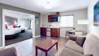 a living room with a couch and a bed and a kitchen at Gibsons Garden Hotel in Gibsons