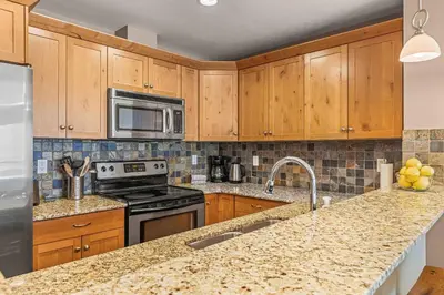 a kitchen with wooden cabinets and a granite counter top at Best Views of Canmore - 2Bed 2Bath in Canmore