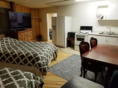 a kitchen with two beds and a table and a refrigerator at Caravan Motel in Fort Saint John