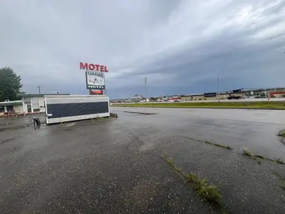 an empty parking lot with a motel sign in the background at Caravan Motel in Fort Saint John