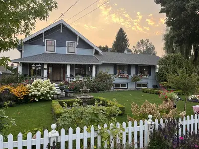 a house with a white fence in front of a yard at The Hazelhouse in Chilliwack