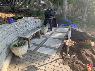 a stone patio with a bench and a grill at Sweetest Suite Downtown in Salmon Arm