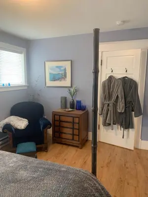 a bedroom with a bed and a door with a chair at Sweetest Suite Downtown in Salmon Arm