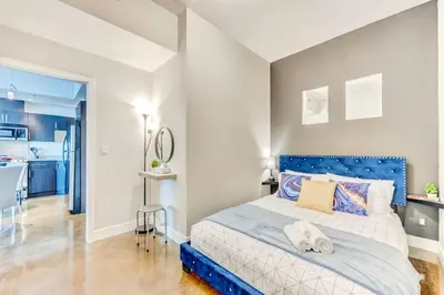 a bedroom with a blue bed and a kitchen at Luxury 2BR Condo - King Bed - Stunning City Views in Calgary