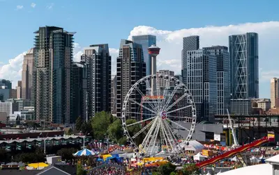 a ferris wheel in front of a large city at Luxury 2BR Condo - King Bed - Stunning City Views in Calgary