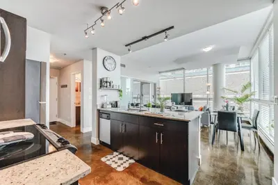 an open kitchen with a dining area and a table at Modern Condo w Balcony - Steps from Stampede Park in Calgary