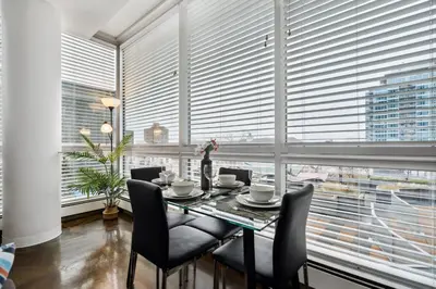 a dining room with a table and chairs and a large window at Modern Condo w Balcony - Steps from Stampede Park in Calgary