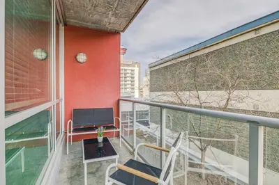 a balcony with a flat screen tv on a building at Modern Condo w Balcony - Steps from Stampede Park in Calgary