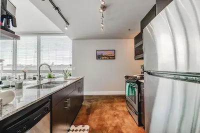 a kitchen with a refrigerator and a sink at Modern Condo w Balcony - Steps from Stampede Park in Calgary