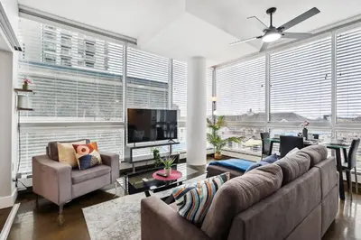 a living room with couches and a tv and large windows at Modern Condo w Balcony - Steps from Stampede Park in Calgary