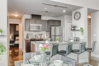 a kitchen and dining room with a table and chairs at Modern Condo w Balcony - Steps from Stampede Park in Calgary