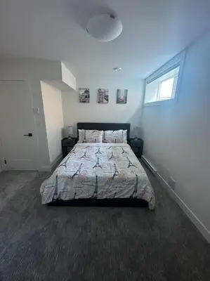 a bedroom with a large bed in a white room at The Royal Bay Escape: Cozy 2 bedrooms garden suite in Colwood