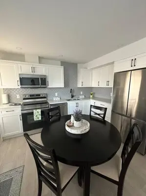 a kitchen with a black table and a refrigerator at The Royal Bay Escape: Cozy 2 bedrooms garden suite in Colwood