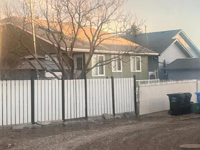 a white fence in front of a house at Cozy 3 beds Suite Near Calgary Airport Sleeps 6 in Calgary