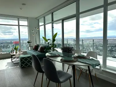 a living room with a table and chairs and windows at Pacific Sweet Place @Metro in Burnaby