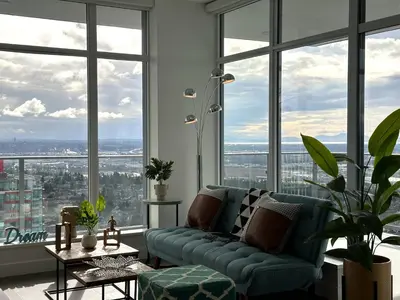 a living room with a blue couch and large windows at Pacific Sweet Place @Metro in Burnaby