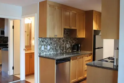a kitchen with wooden cabinets and a black counter top at The Après Suite in Whistler