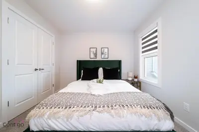 a bedroom with a large bed with white walls and a window at Orchards Retreat, AC, Family Friendly, Sleeps 10, NearAirprt in Nisku