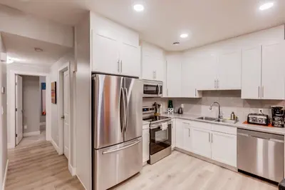 a kitchen with white cabinets and a stainless steel refrigerator at Modern suite near Airport Hospital Henday Town Ctr in Nisku