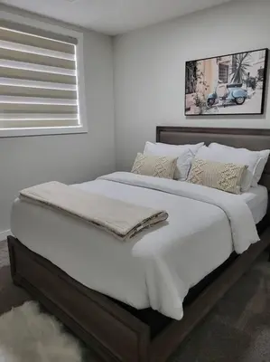 a white bedroom with a large bed with white sheets and pillows at Serene Haven - 1 bedroom apartment. in Calgary