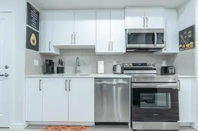 a kitchen with white cabinets and stainless steel appliances at Stylish Getaway 2BD Basement by YMCA and South Health Campus Hospital in Calgary