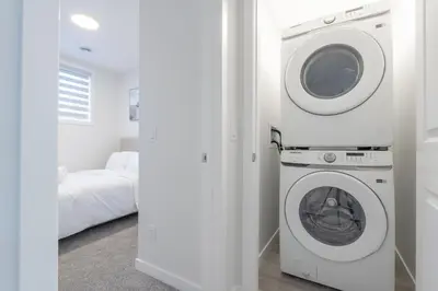 a white washer and dryer in a bedroom at Stylish Getaway 2BD Basement by YMCA and South Health Campus Hospital in Calgary
