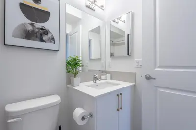 a bathroom with a sink and a toilet and mirrors at Stylish Getaway 2BD Basement by YMCA and South Health Campus Hospital in Calgary