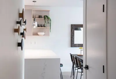 a white kitchen with a counter and a table at The Monashee House by Revelstoke Vacations in Revelstoke