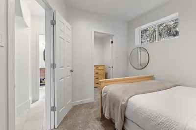 a white bedroom with a bed and a mirror at Private Mountainside Home in Chilliwack