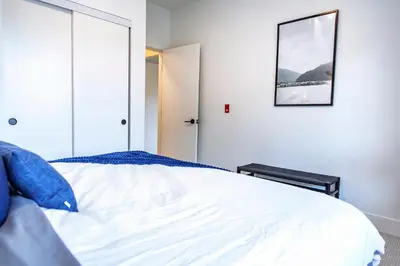 a bedroom with a white bed with a picture on the wall at Revy's Stellar Retreat in Revelstoke