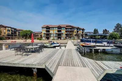 a dock with a table and chairs and a boat on the water at Lakeside Luxe Haven in West Kelowna