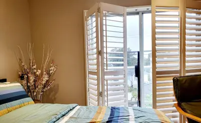 a bedroom with a window with shutters and a bed at Vivi's Home in Vancouver