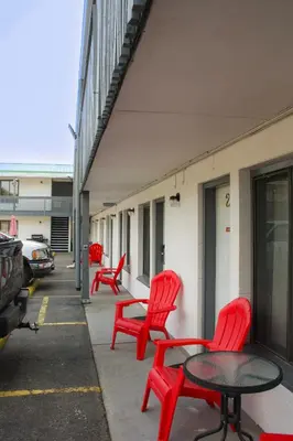a group of red chairs and a table on a sidewalk at Granby River Inn & Suites in Grand Forks