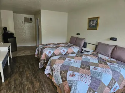 a hotel room with two beds and a desk at Granby River Inn & Suites in Grand Forks