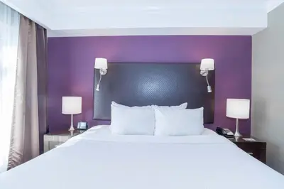 a bedroom with a large white bed with a purple headboard at Sandman Signature Kamloops Hotel in Kamloops