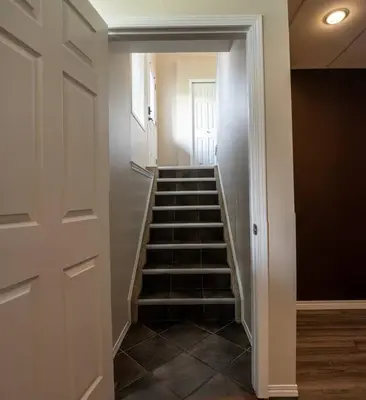 a hallway with a staircase in a house at Pink door-ed wonder in Grande Prairie
