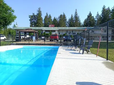 a swimming pool with chairs in front of a building at Clearwater Country Inn in Clearwater