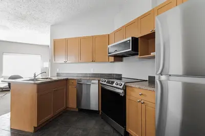 a kitchen with wooden cabinets and a stainless steel refrigerator at Premier Residence - Fort McMurray in Fort McMurray