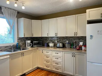 a kitchen with white cabinets and a white refrigerator at Beautiful room close Airport! in Calgary