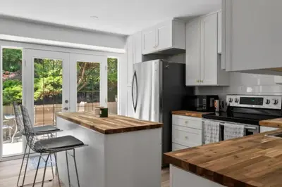 a kitchen with white cabinets and a wooden counter top at Mid-Century Modern Dream Retreat in West Kelowna