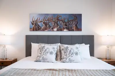 a bedroom with a white bed with deer paintings on the wall at Revylation by Revelstoke Vacations in Revelstoke