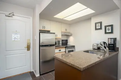 a kitchen with a sink and a refrigerator at 1BR in Marquise, Close to Ski Hill, Pool, Sauna, Hot Tub, Fitness Suite, Fireplace in Whistler