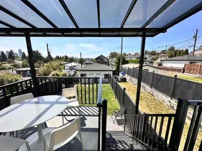 a patio with a table and chairs on a balcony at Modern and New house near PNE with Big Garden and Free Parking in Vancouver