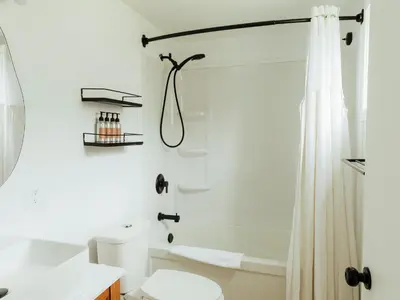 a white bathroom with a shower and a toilet at Ucluelet Wildwood Inn in Ucluelet