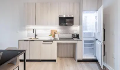 a kitchen with white cabinets and a refrigerator at Steveston Waterfront Hotel in Richmond