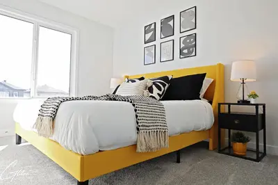 a bedroom with a yellow bed with black and white pillows at Beautiful 3 King Beds,Garage,Airport,Disney+ in Edmonton