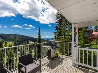 a patio with a grill and chairs on a balcony at The Alpine I No Service Fee's I Ski-in Ski-Out I in Silver Star