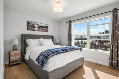 a bedroom with a bed and a large window at Bright & Spacious 3 Beds Luxury Home in SE Calgary in Calgary