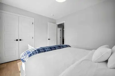 a white bedroom with a white bed with a blue pillow at Bright & Spacious 3 Beds Luxury Home in SE Calgary in Calgary